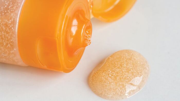 Orange facial scrub wash on white tile