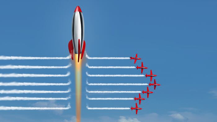 Thinking big business concept as a large rocket blasting through the smoke of a group of jet air planes as a financial metaphor for corporate winner as a 3D render.
