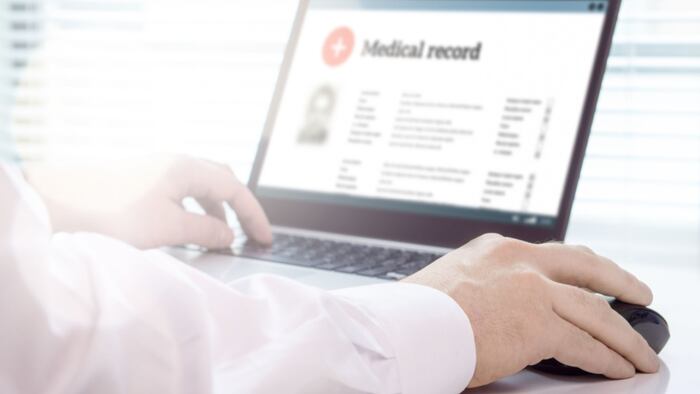 Doctor using laptop and electronic medical record (EMR) system. Digital database of patient's health care and personal information on computer screen.