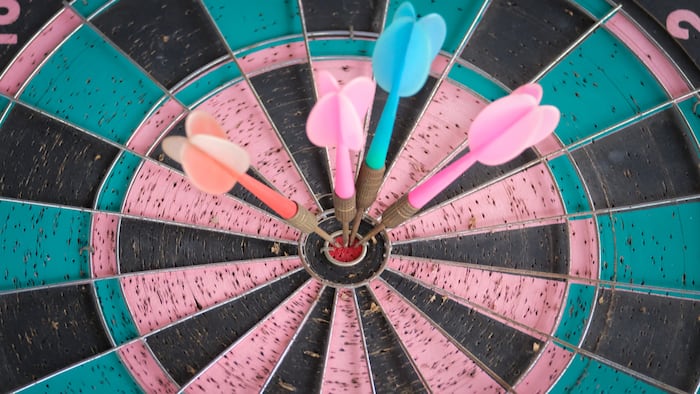 Four darts arrows hitting in the target center dartboard. Success business goal concept