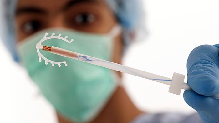 Young doctor holding an IUD birth control copper coil device in hand, used for contraception