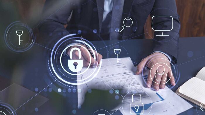 A businessman in formal wear signing a contract. Padlock Hologram icons over the working desk.