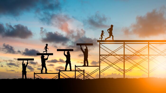 Adults help build a foundation in silhouette