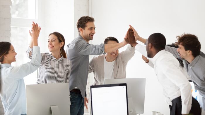 Excited multiracial colleagues celebrating team victory giving high five in office, happy employees group join hands together promising loyalty engagement, expressing trust unity support in teamwork
