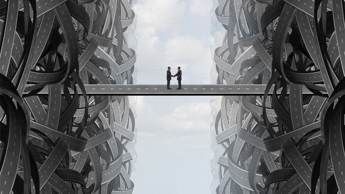 Agreement business handshake partnership deal as a solution strategy with a team coming together out of tangled twisted roads on to a bridge to find a common goal.
