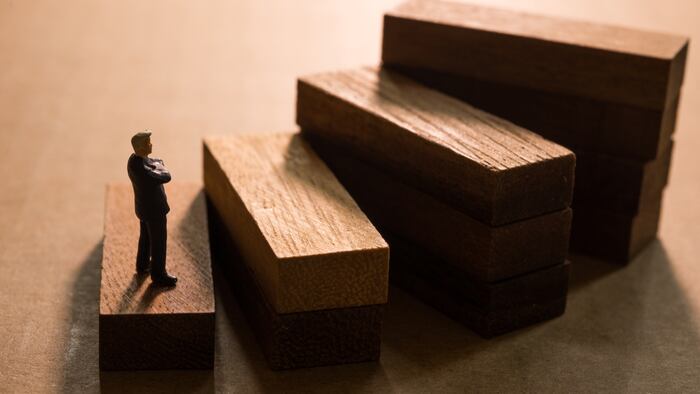 A figurine of a man contemplating walking up wooden steps