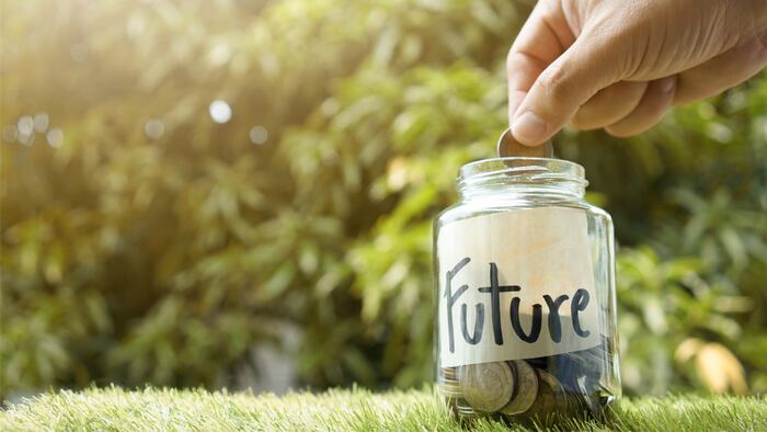 Money saving, Hand putting coin in glass jar with coins inside For now and future money. Concept of saving money for future. - Image