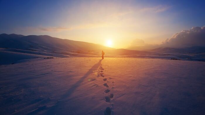 Walking away in a desert, leaving footprints in the sand