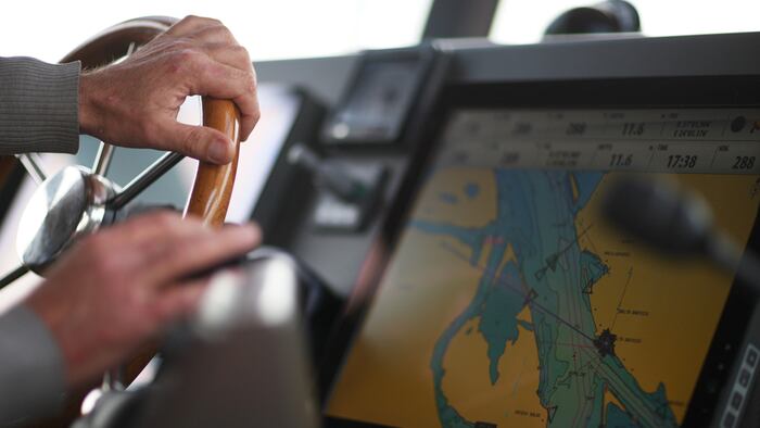 The hands of the captain and a steering wheel boat port services
