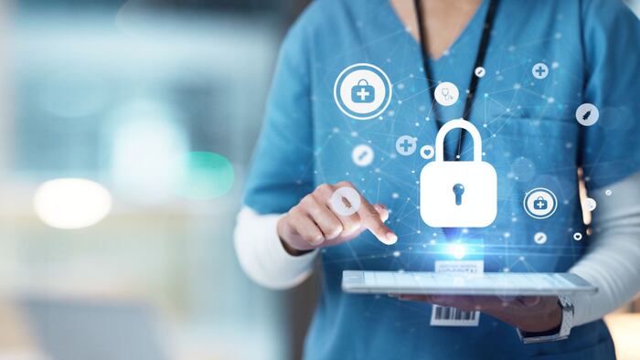 A female nurse types on an tablet while icons of locks float above the screen