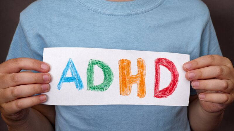 Young boy holds ADHD text written on sheet of paper. ADHD is Attention deficit hyperactivity disorder. Close up. - Image