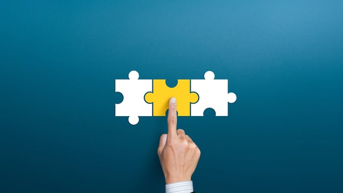 Person's hand connecting puzzle pieces