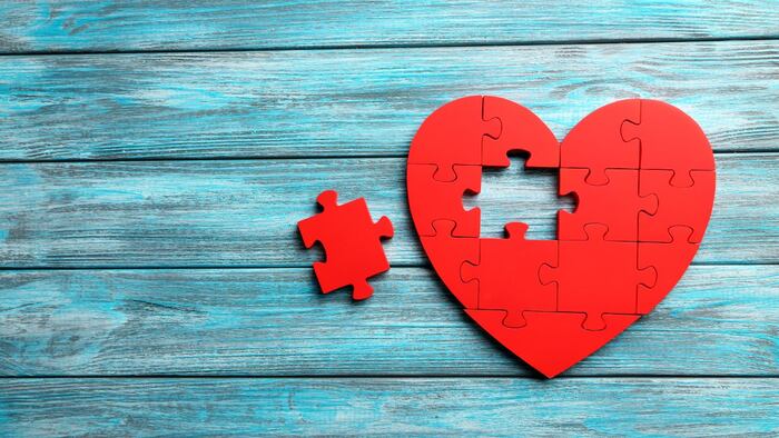 Heart made out of red puzzle pieces with one piece missing
