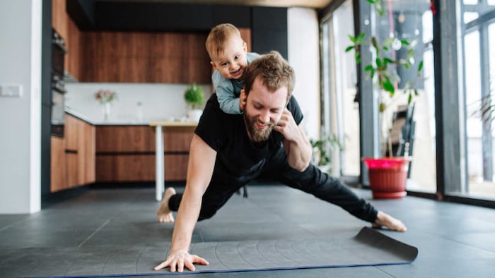 man doing one arm push up with child on back