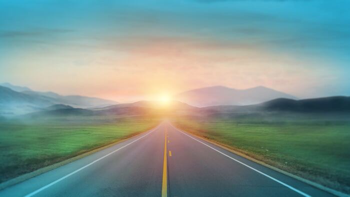 Mountain road. Landscape with green field, sunny sky with clouds and beautiful asphalt road in the morning. Scenic background.