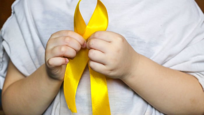 close up of person's arms holding yellow ribbon