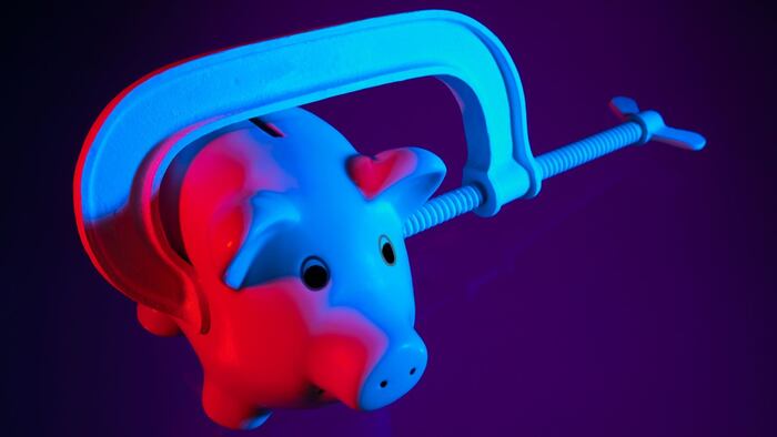 Credit squeeze concept - piggy bank in clamp