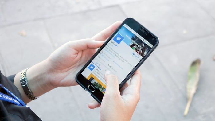 Women hand holding smartphone and using Twitter application