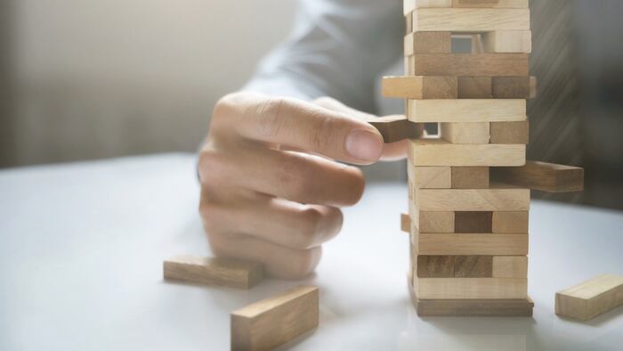 Hand of business man planning, risk and strategy in business.Businessman gambling placing wooden block on a tower.