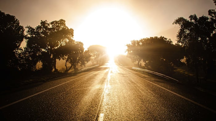 Tar road with sun ahead