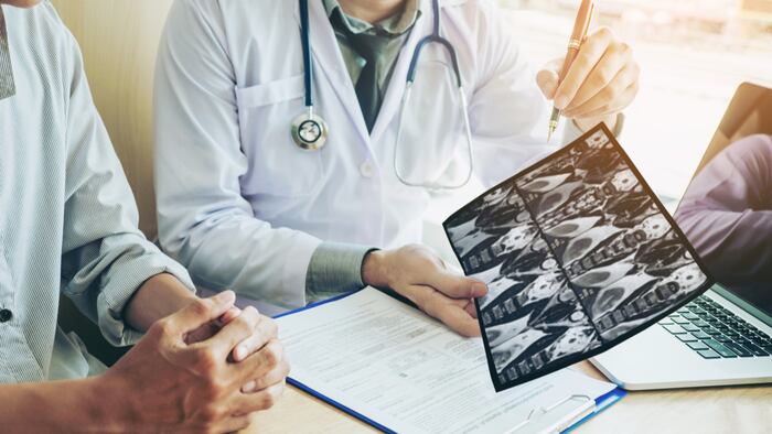 Doctor consulting with patient presenting results on x-ray film About the problem of the patient - Image