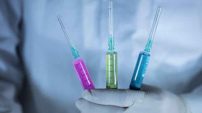 The doctor is holding three vaccines. Vaccines in red and green colors.