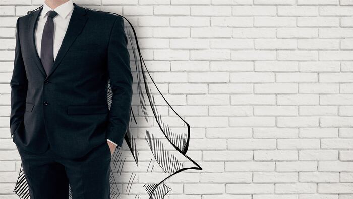 Businessman with drawn cape on white brick background. Leadership concept