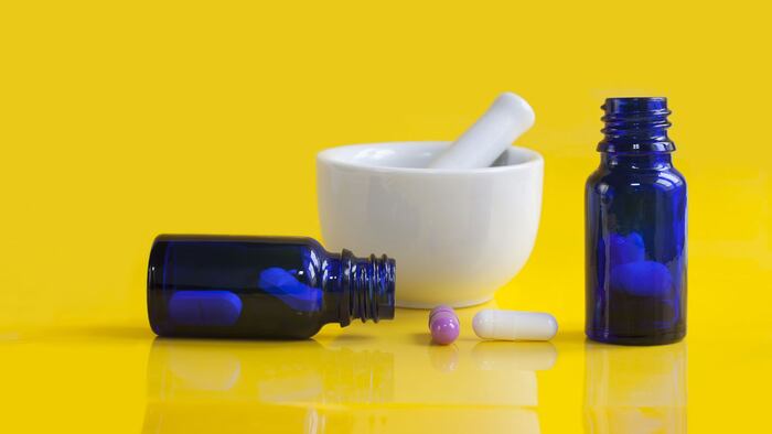 capsules in blue glass container on yellow background