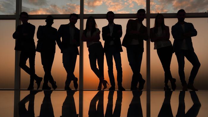 Executive leadership team in silhouette in front of a window
