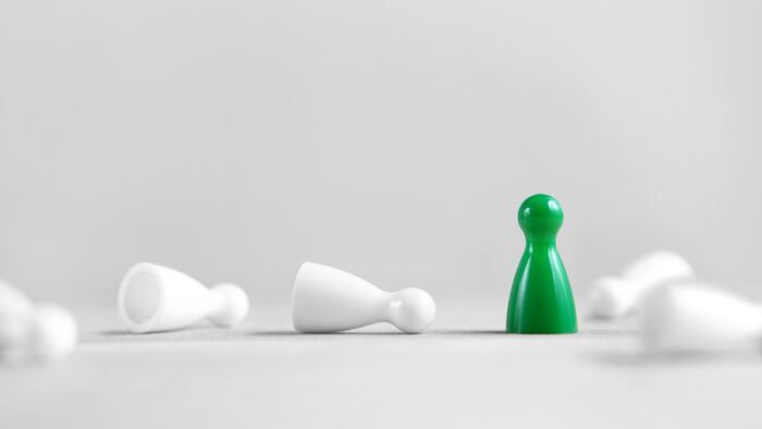 Winning, victory, success and surviving concept. Green board game pawn stand alone, the white rest fallen. Eliminating competitors. One against the others. Last man standing. Against all odds.