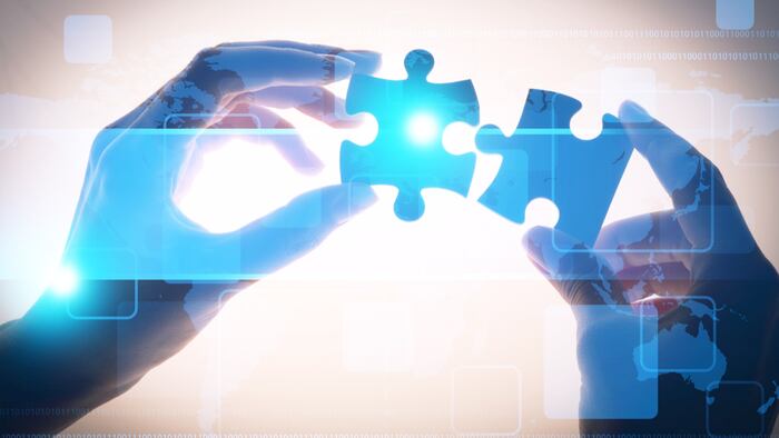 strategy concept - hands holding back-lit blue puzzle pieces coming together