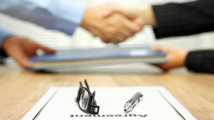 businessman and businesswoman are shaking hands and exchanging folder after agreement was reached