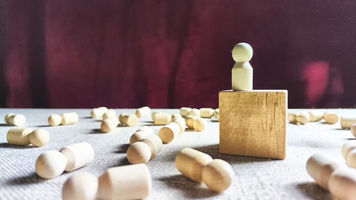 Single wooden figure among lying figures on ground