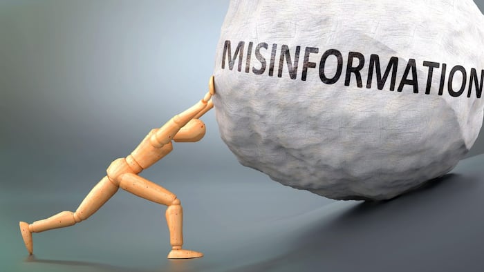 Wooden man pushing misinformation rock uphill