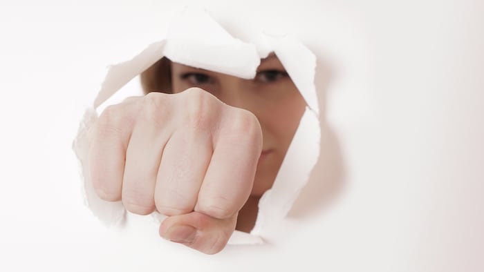 woman punching hole through paper wall with fist