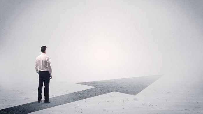 A professional businessman thinking while standing on a black arrow pointing forward in grey space concept