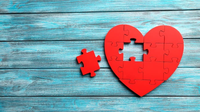Heart made out of red puzzle pieces with one piece missing
