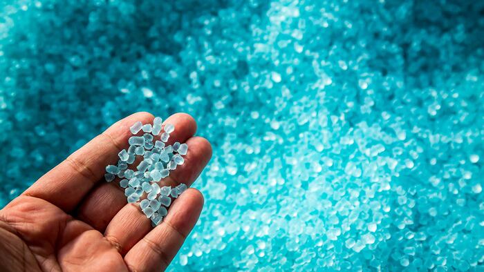 A hand touching plastic polymer dye granules.