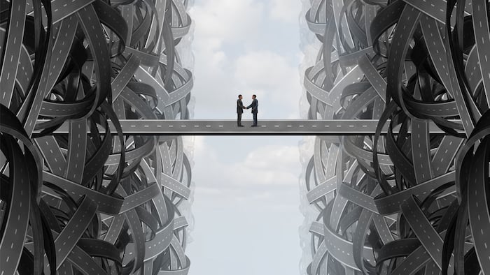 Agreement business handshake partnership deal as a solution strategy with a team coming together out of tangled twisted roads on to a bridge to find a common goal.
