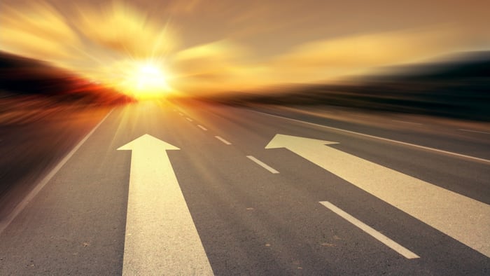 Arrows on road pointing to sunrise
