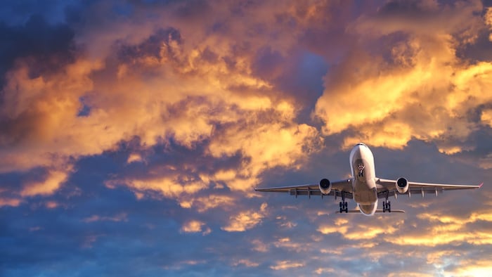 Passenger airplane is flying in colorful sky at sunset