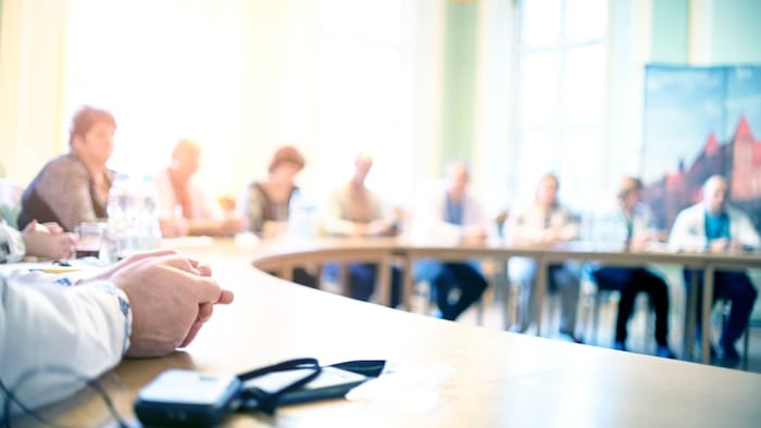 blurred image of people meeting around a oval shaped table