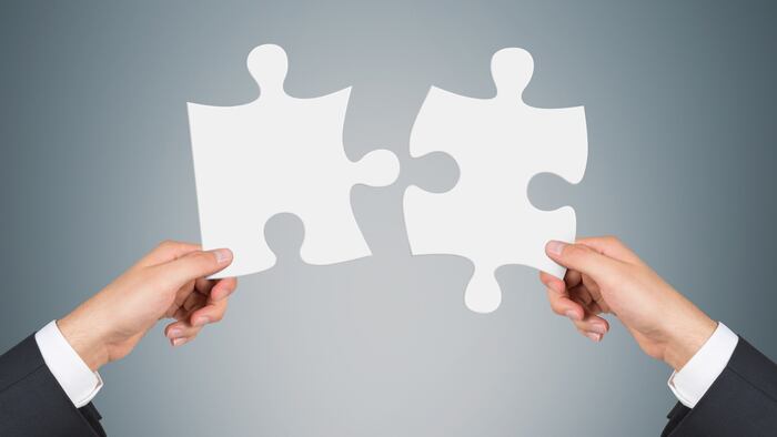 Alliance concept - two businessmen put blank puzzle pieces together