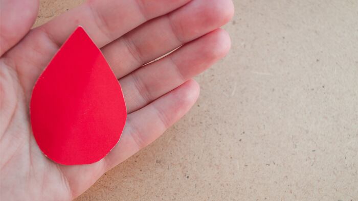 Hand holds a drop of blood. World Hemophilia Day. World Blood Donor Day.