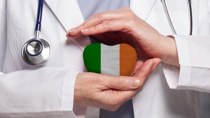 Irish doctor holding heart with flag of Ireland background. Healthcare, charity, insurance and medicine concept