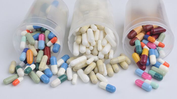 assortment of pills and capsules of colors in plastic jars isolated in white - Image