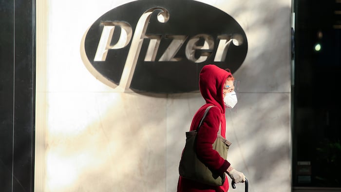 A woman wears a facemask as she walks by the Pfizer world headquarters in New York on November 9, 2020.