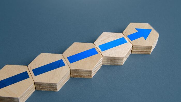 Blue arrow on wooden hexagons, adding expanding concept