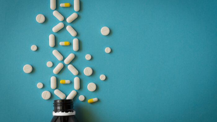 white pills with bottle on blue background. genetic diseases concept