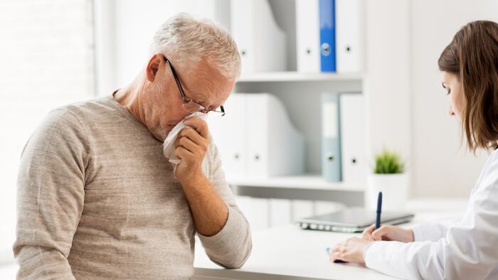 medicine, age, health care, flu and people concept - senior man blowing nose with napkin and doctor with clipboard writing at medical office at hospital - Image
